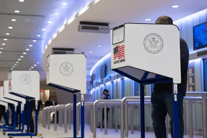 A number of voting privacy screens are seen in a lobby area of Madison Square Garden, with one voter voting